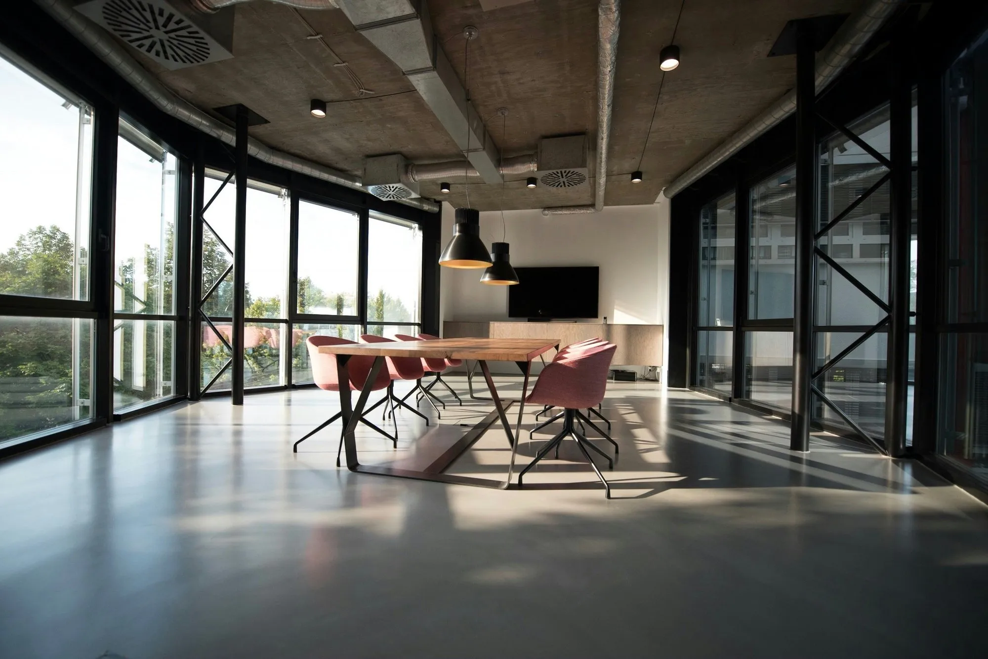 Bright open office with glass meeting rooms and a long island table