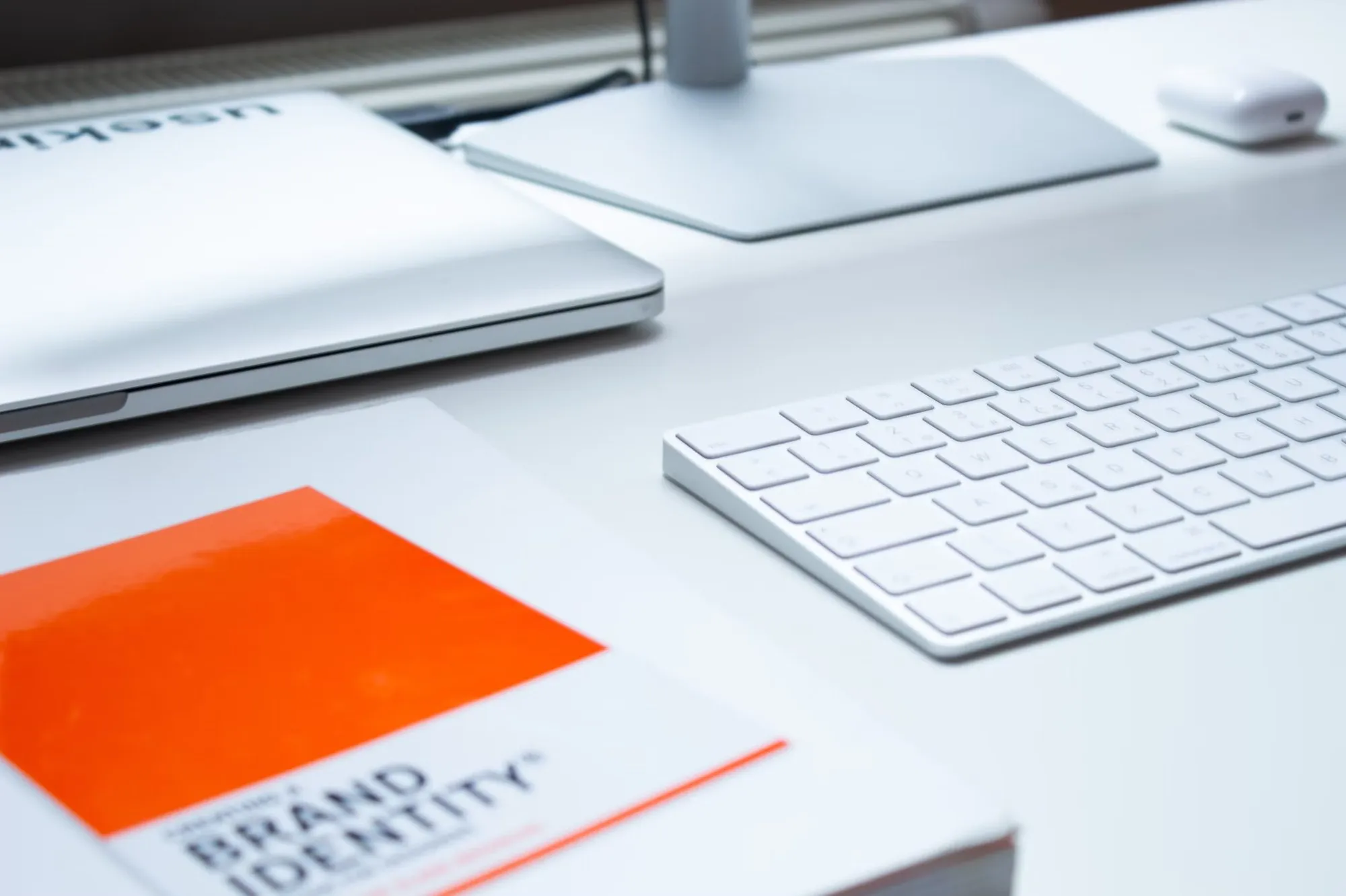 Brand identity booklet with an orange cover next to a white keyboard and trackpad