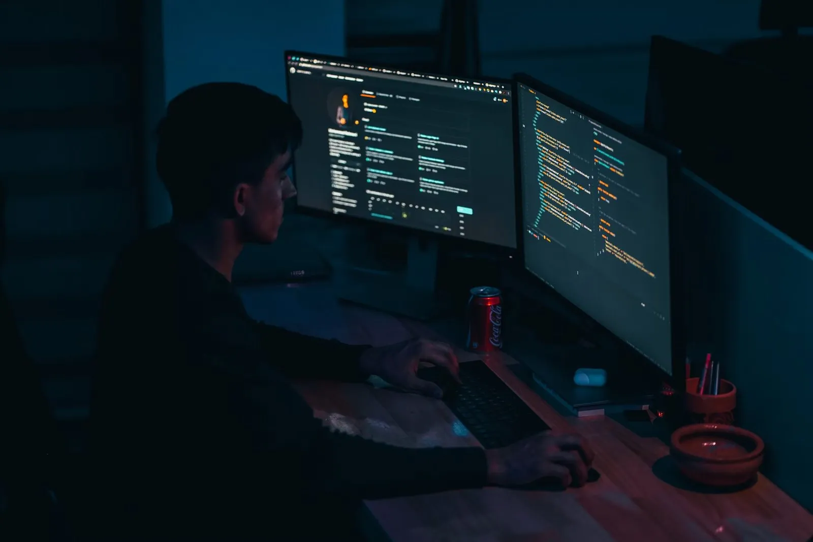 Developer working at two monitors in a dark room